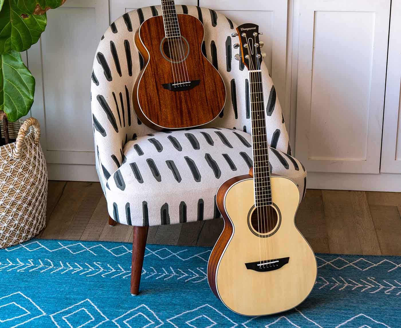 Dana mahogany and dana spruce guitars on a white chair 